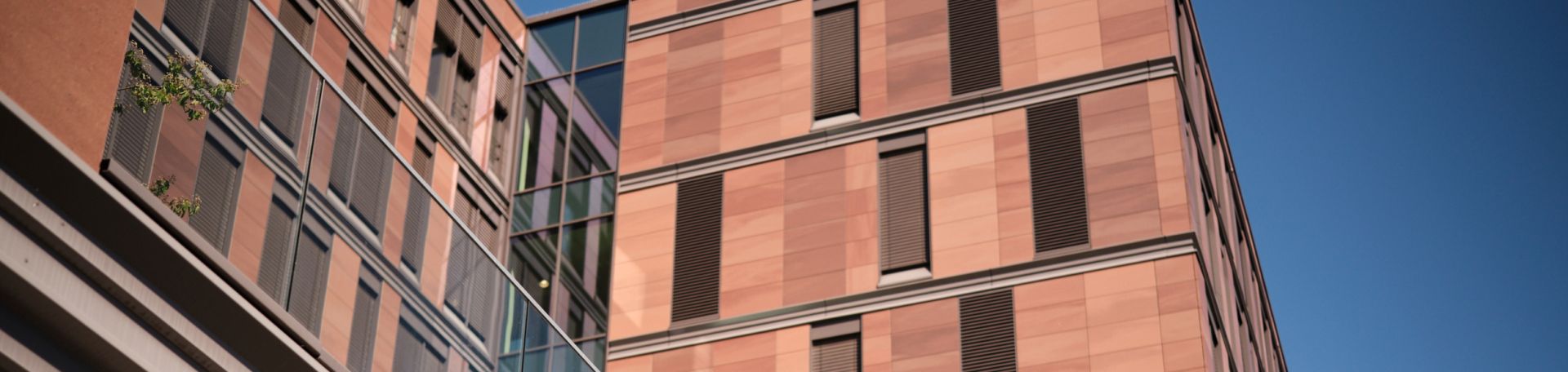 A partial section of the FS building is shown. The modern reddish-brown facade contrasts with the blue sky.