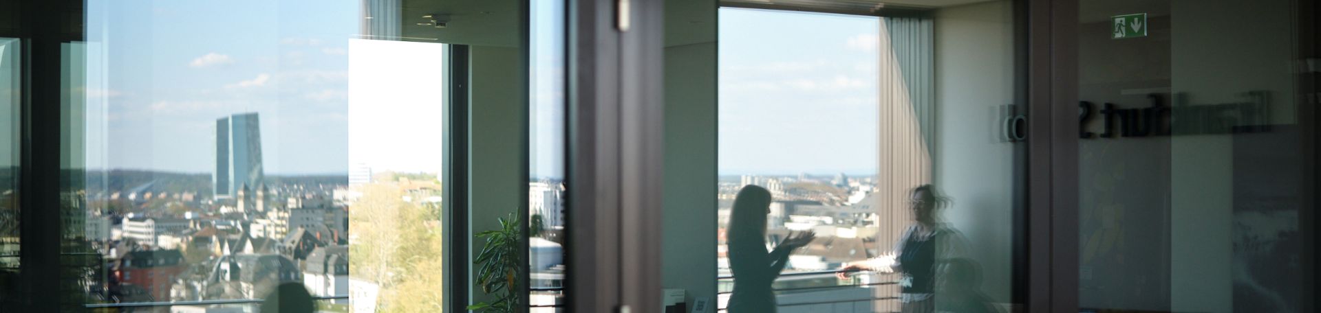 A large window reflects a scene showing two people conversing at the FS.