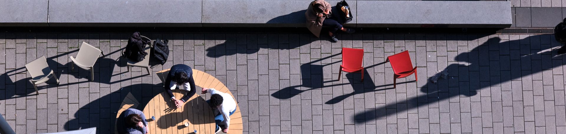 From a bird's eye view, you can see the terrace area of the FS canteen. You can see people and sunshades.